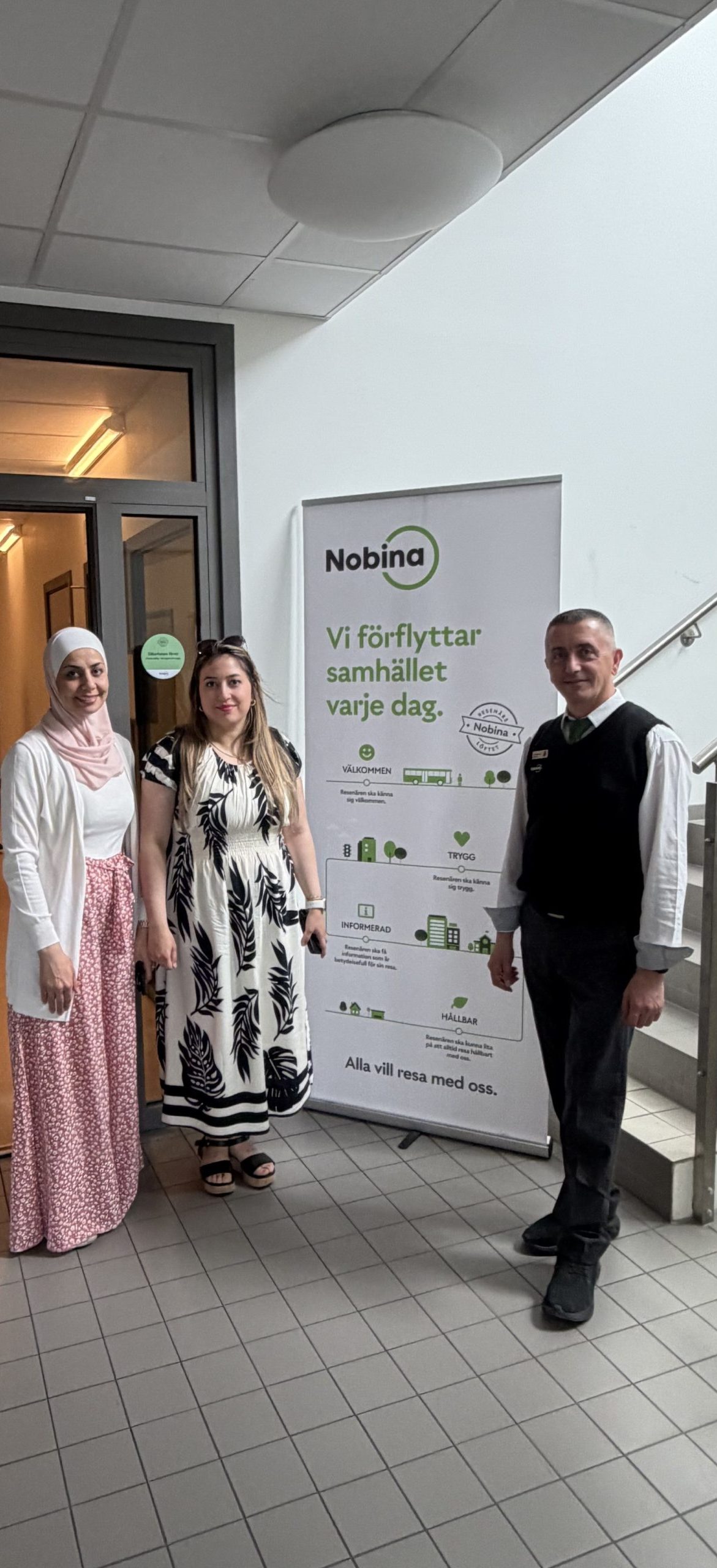 Eductus två handledare och representant från Nobina står vid en roll-up och vända mot kameran och ler